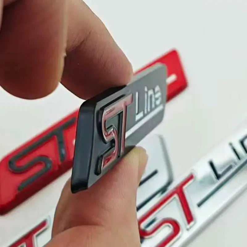 ST Line 3D metal badge, black base with chrome-silver lettering, rear trunk emblem