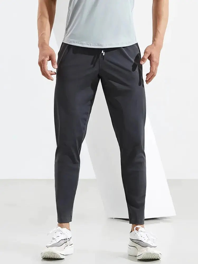 Men's running pants by Simples Market; dark gray quick-dry joggers with drawstring and elastic cuffs.