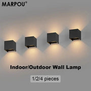 MARPOU four black cube LED wall lamps mounted in a row with warm ambient lighting; indoor/outdoor wall light set.
