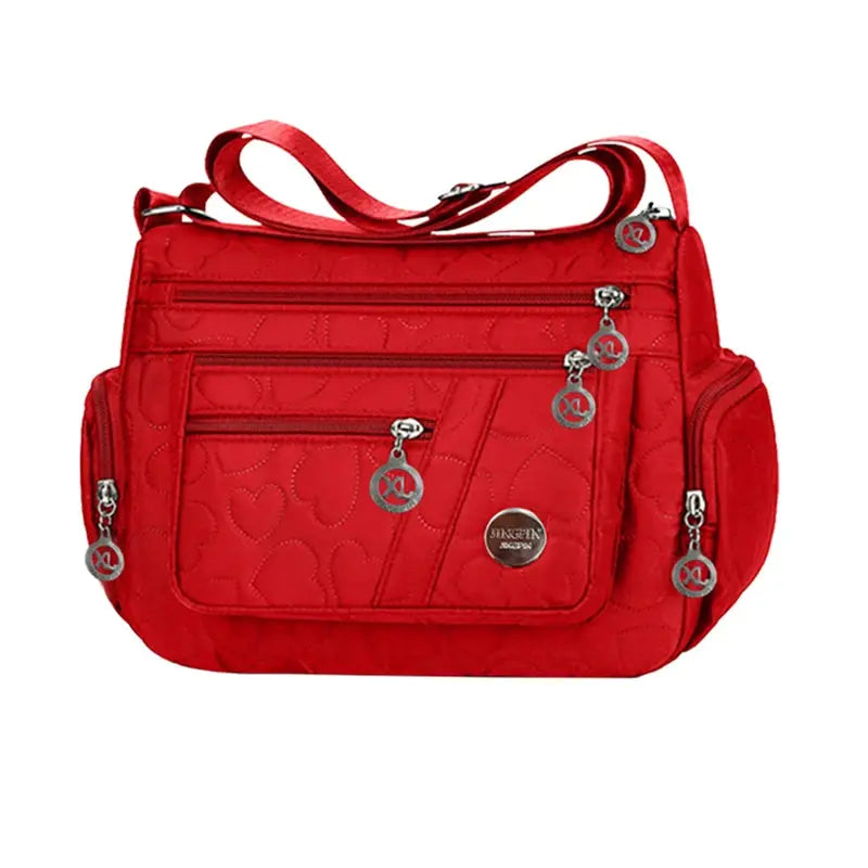 Handbag in red nylon with crossbody strap and multiple zip pockets, quilted heart pattern