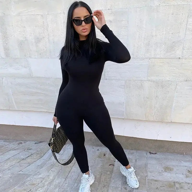 Solid black long-sleeve women's jumpsuit, form-fitting athletic one-piece streetwear outfit.