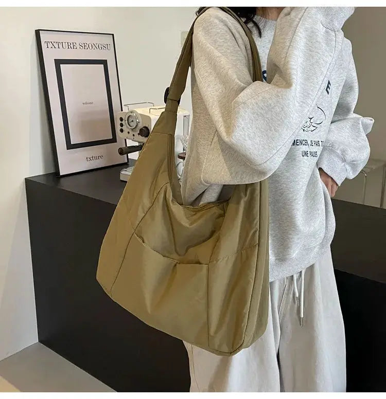 Simples Market soft-cloth shoulder bag, beige oversized crossbody carried by a woman in a gray hoodie