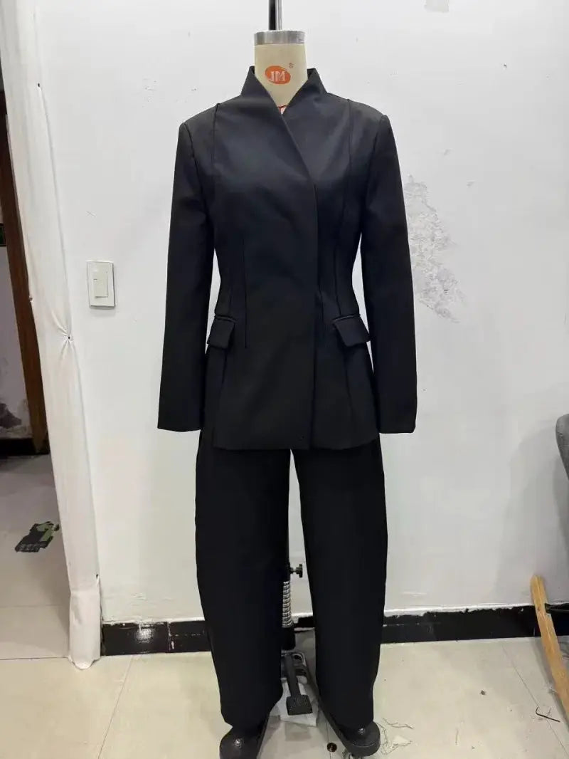 Simples Market ETJ 2025 black women's suit jacket with matching trousers, structured three-dimensional cut, high collar.