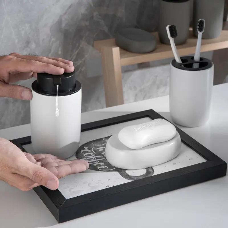 Ceramic four-piece bathroom set with mouthwash cup, sanitizer bottle, toothbrush rack, and soap dish in white and gray.