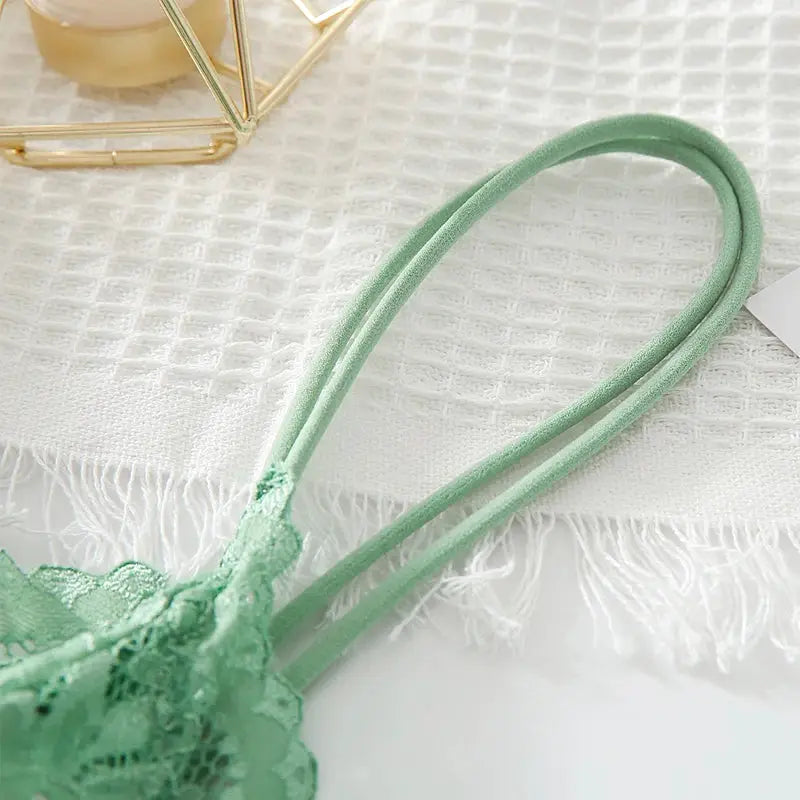 Mint-green lace bralette from Simples Market with double straps on white textured background.