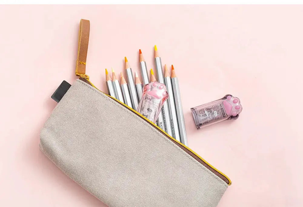 Kawaii cat paw pencil sharpeners (2) in pink translucent plastic beside beige zip pencil case