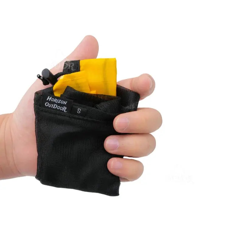 Mesh stuff sack Horizon Outdoor, black pouch with visible yellow interior, held in a hand, drawstring closure