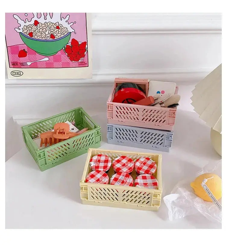 Folding plastic storage baskets for desk organization; four pastel crates in green, pink, blue and yellow with lattice sides.
