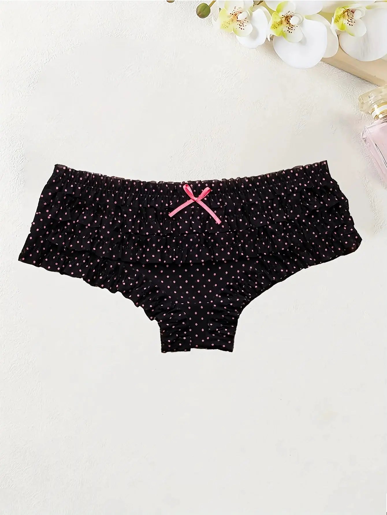 Black women's low-rise briefs with pink polka dots and a pink bow, ruched edges
