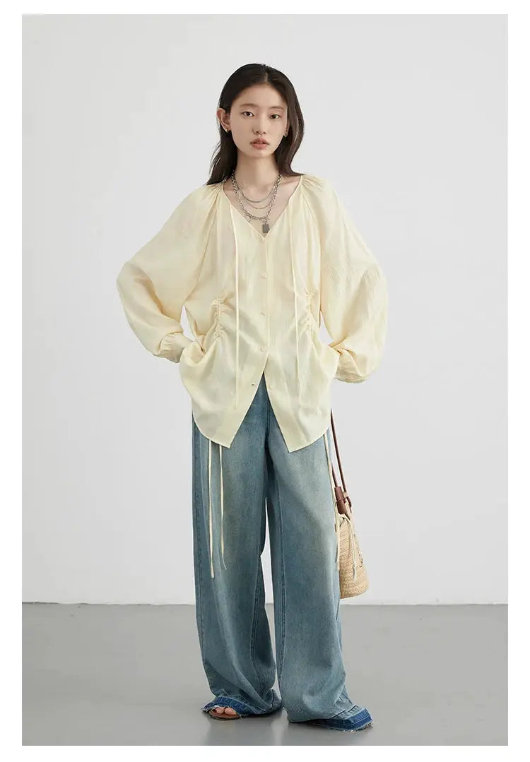 CHIC VEN cream loose lace-up shirt with V-neck and puff sleeves; worn with one pair of wide-leg denim jeans.