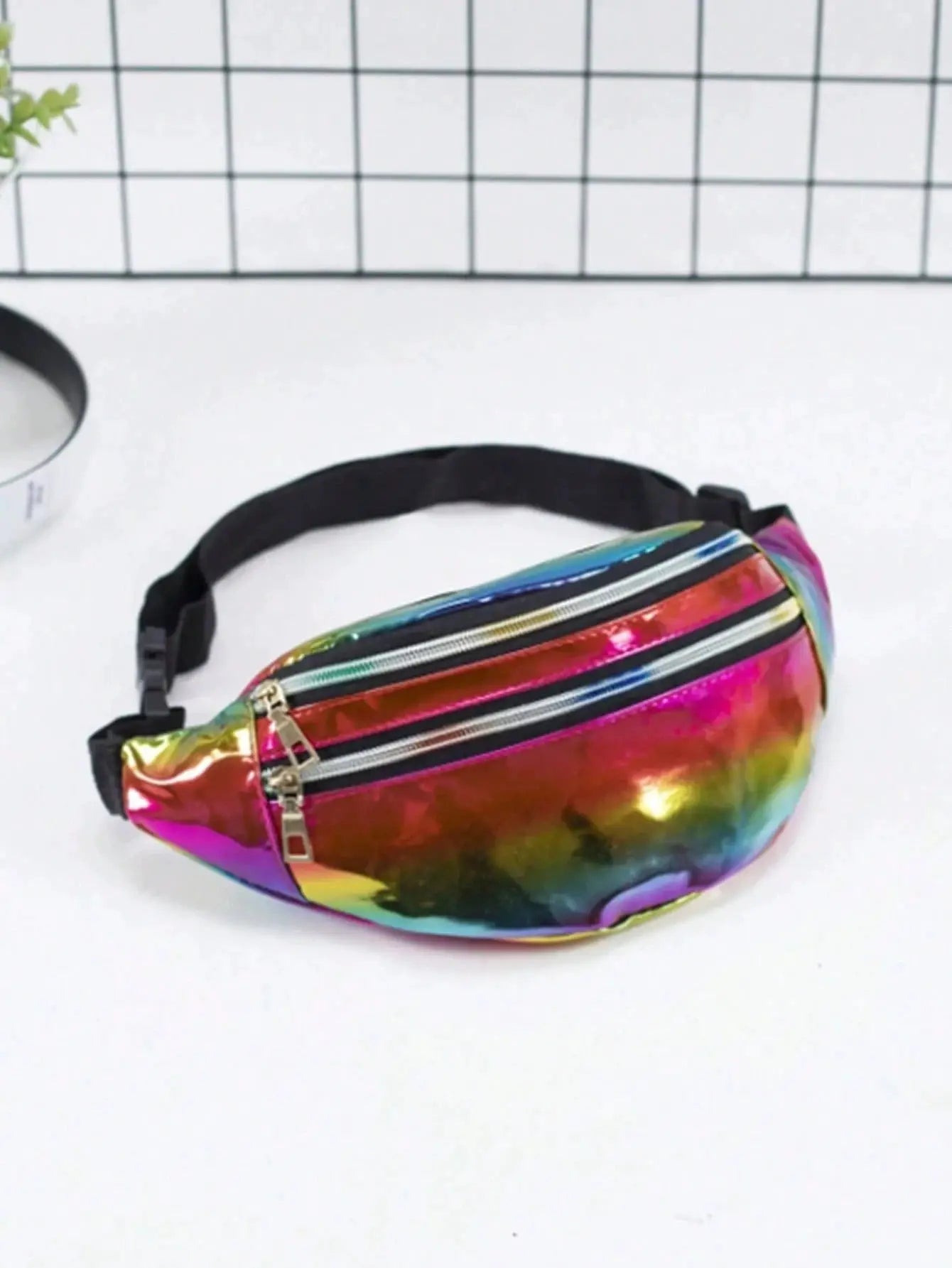 Holographic waist bag by Simples Market with rainbow finish and black strap.