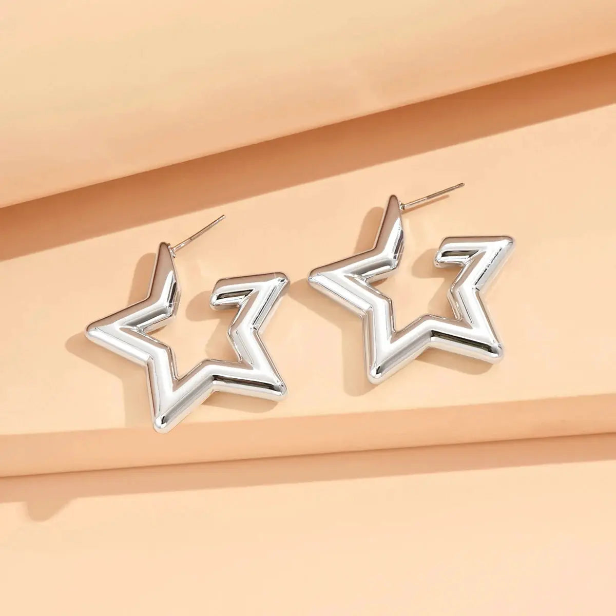 Pair of silver geometric star-shaped stud earrings with thick hollow outlines