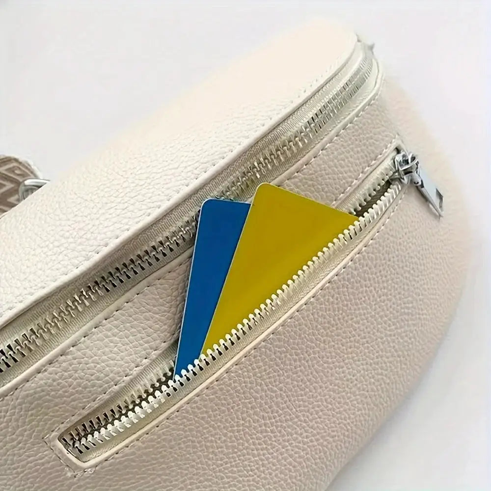 Soft cream leather fanny pack with dual zippers; compact saddle bag with blue and yellow cards tucked in side pocket.