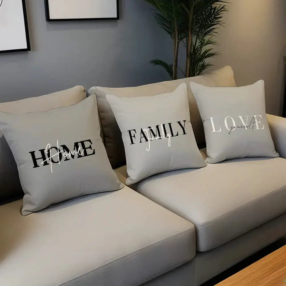Three light-gray pillow covers with HOME, FAMILY, LOVE typography on a sofa.