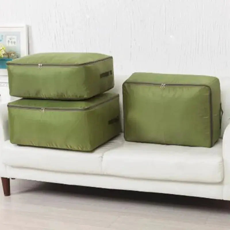 Large zipper clothes organizer bags, set of three, olive green on a white sofa for bedding storage.