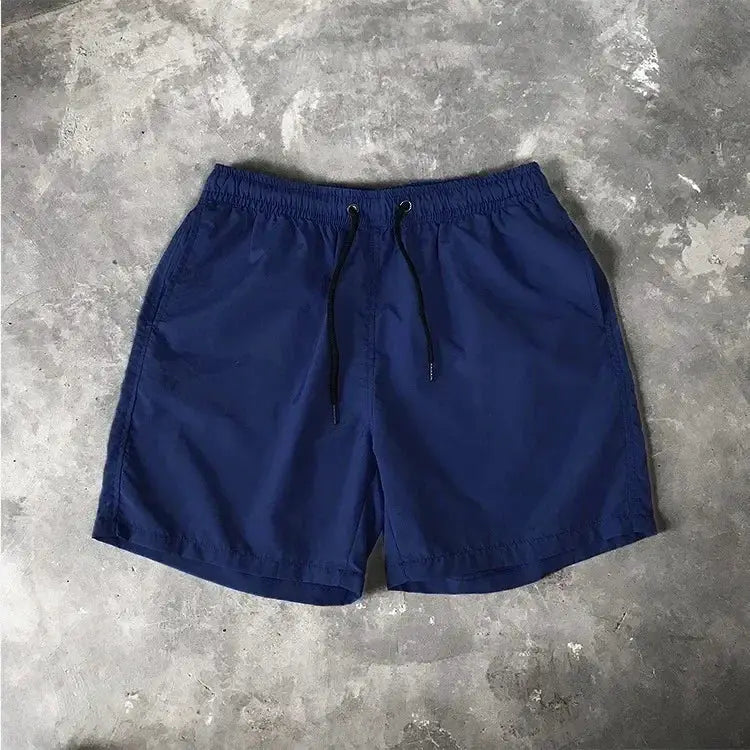 Men's navy blue swim shorts with black drawstring, elastic waistband, mid-length beach trunks for swimming.
