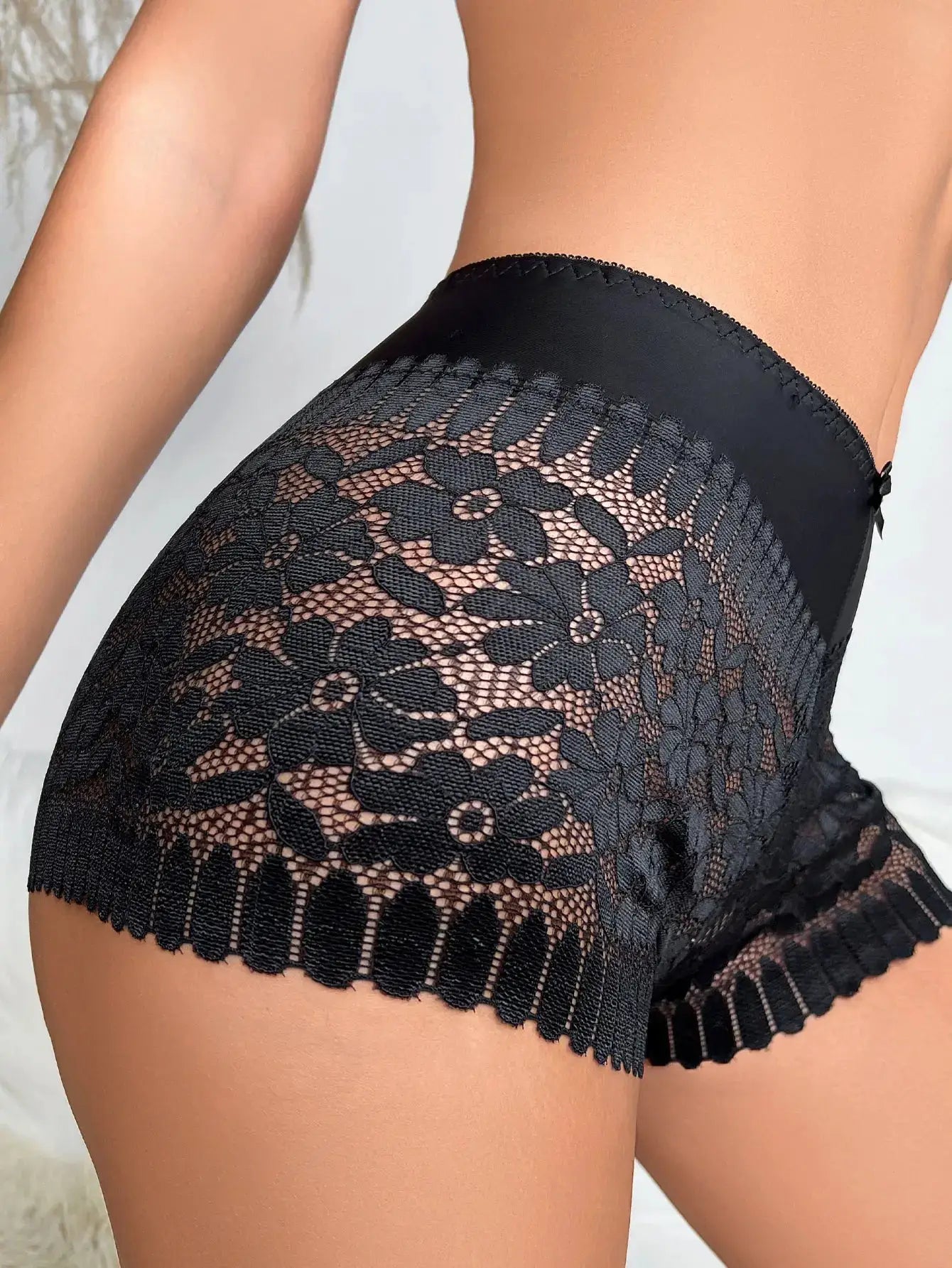 Black lace high-waist panties with floral pattern and scalloped hem.