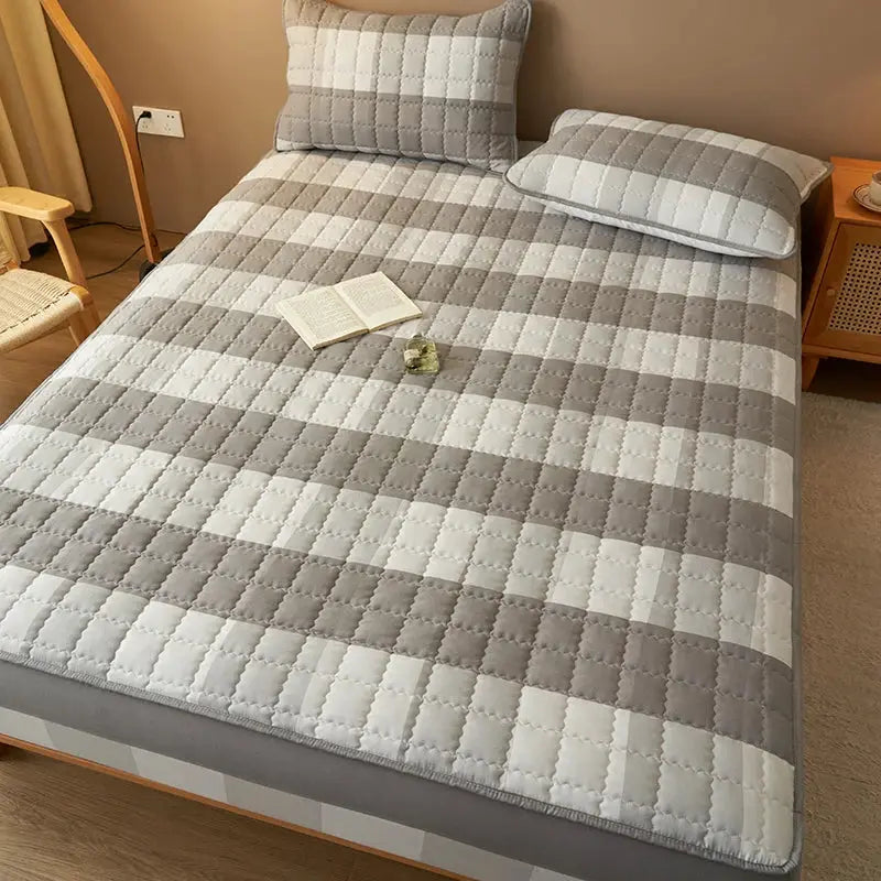 Simples Market quilted plaid mattress protector on bed; antibacterial, breathable gray-white checkered design.