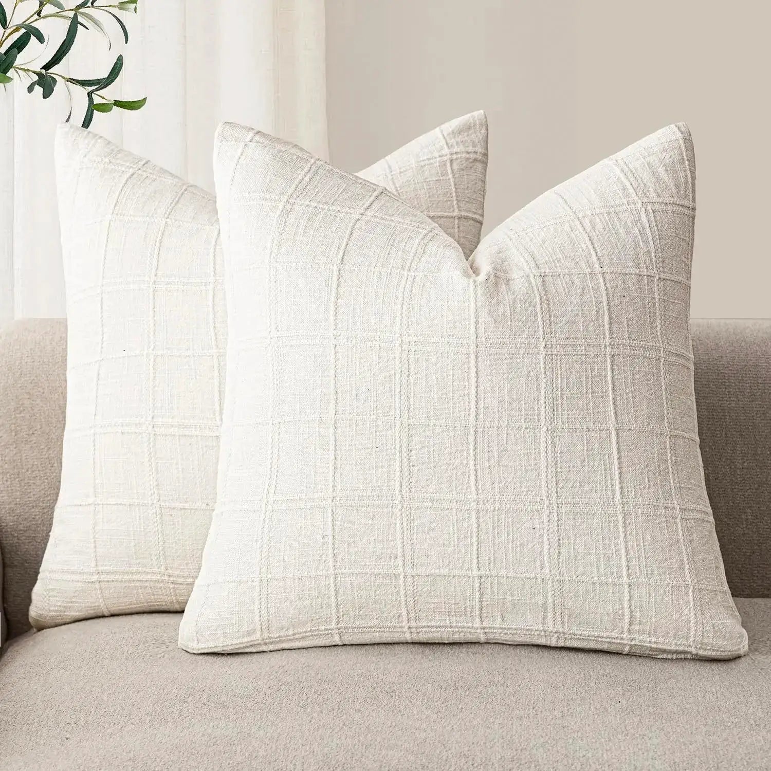 Beige linen square cushion covers with a grid plaid pattern on a neutral sofa