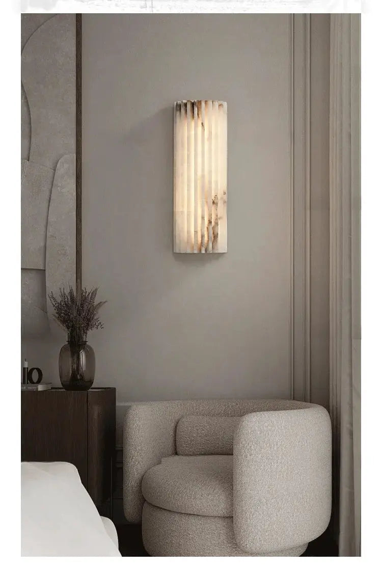 Marble wall lamp with vertical ribbed design; modern minimalist bedside sconce emitting warm light