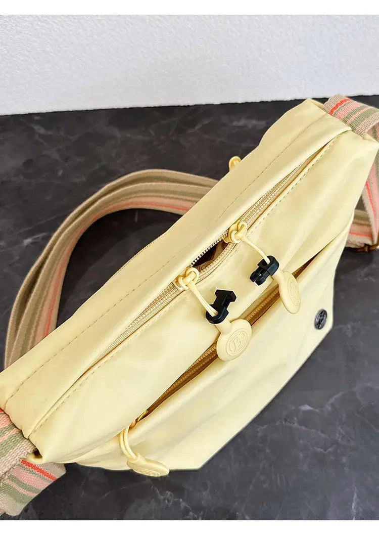 Ultra-light nylon crossbody bag for women by Simples Market with adjustable striped strap and yellow zipper closure