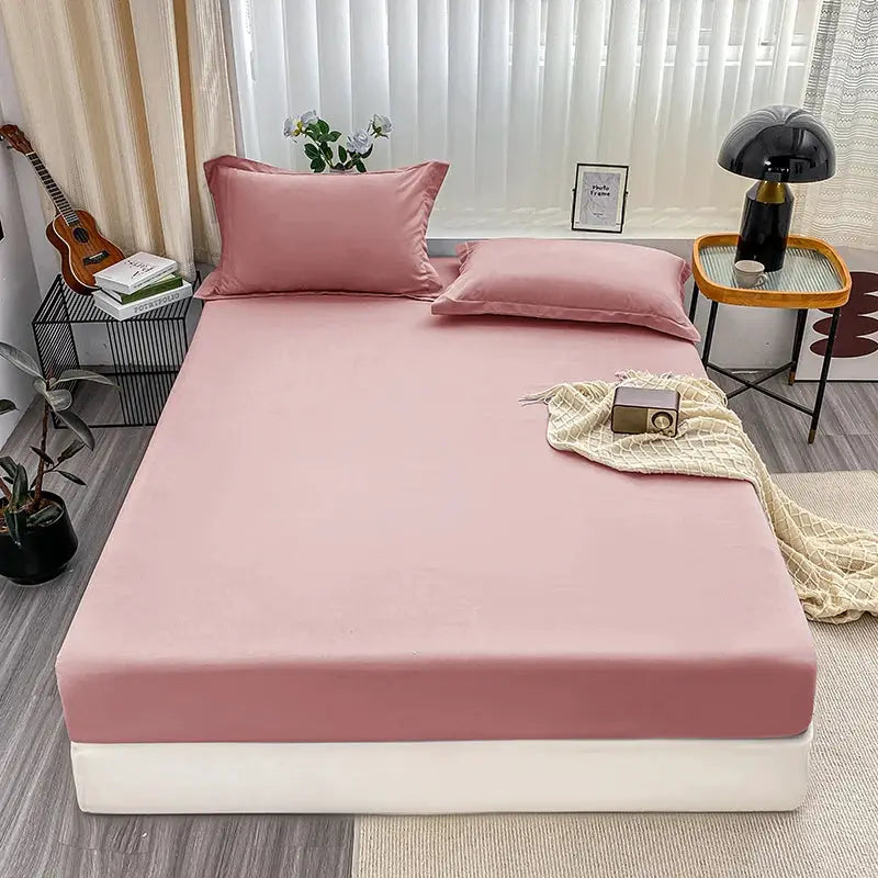 Pink fitted bed sheet with elastic anti-slip band on a neatly made bed; solid color for single to king beds.