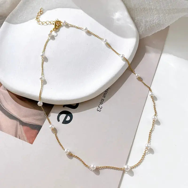 Pearl choker necklace in gold-tone with spaced white beads on a delicate chain