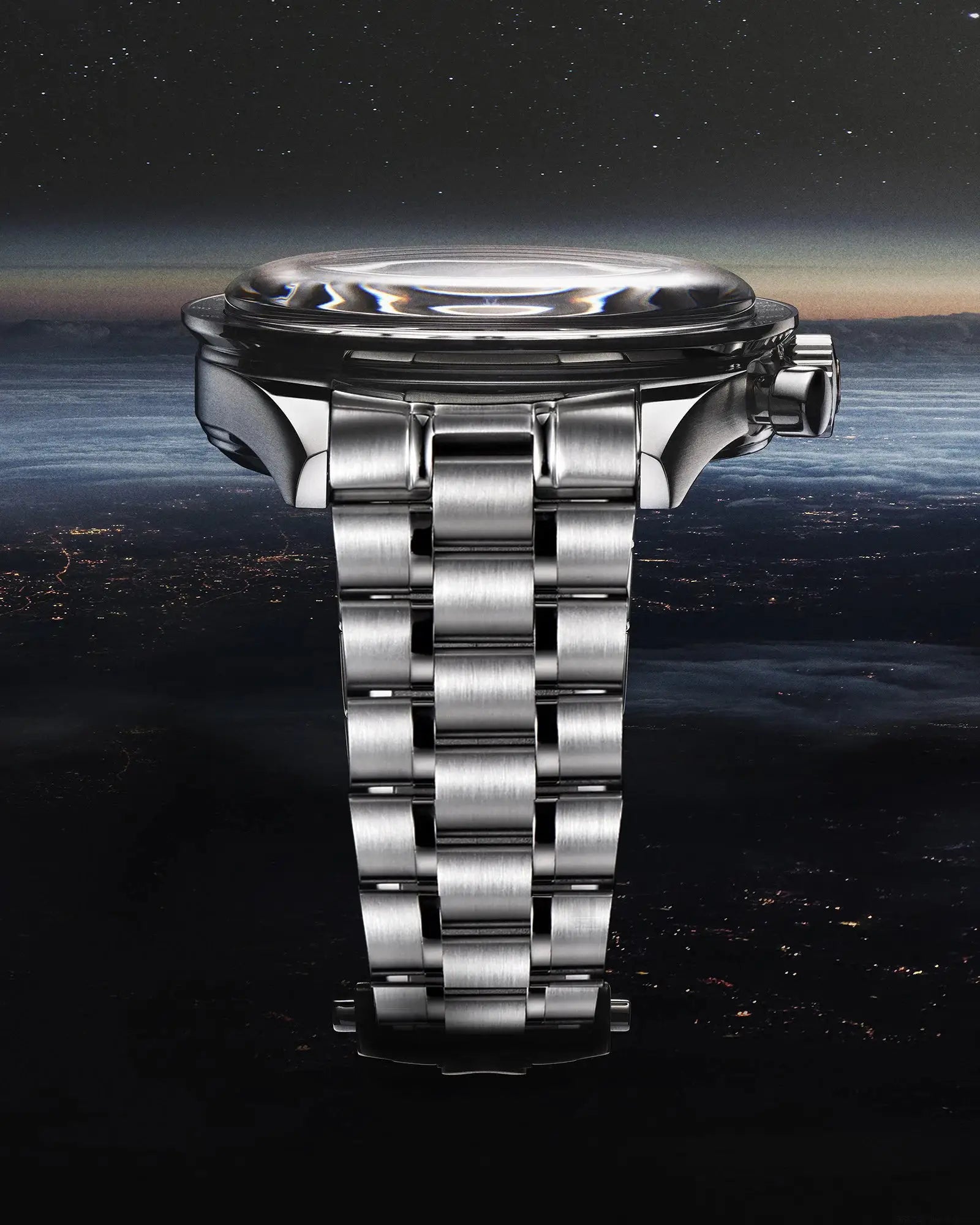 Stainless steel men's wristwatch with polished bracelet and crown, side view close-up.
