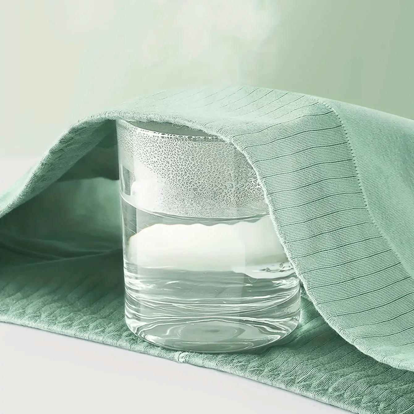 Mint green high-waisted underwear fabric draped over a glass of water