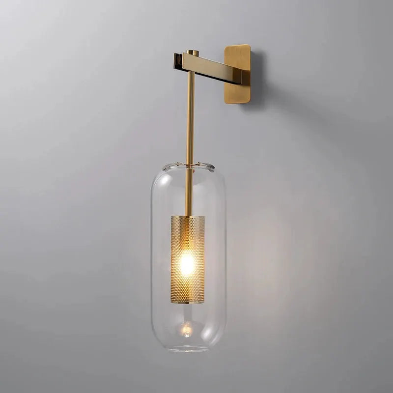Modern glass wall sconce from Simples Market with brass arm and clear cylindrical shade