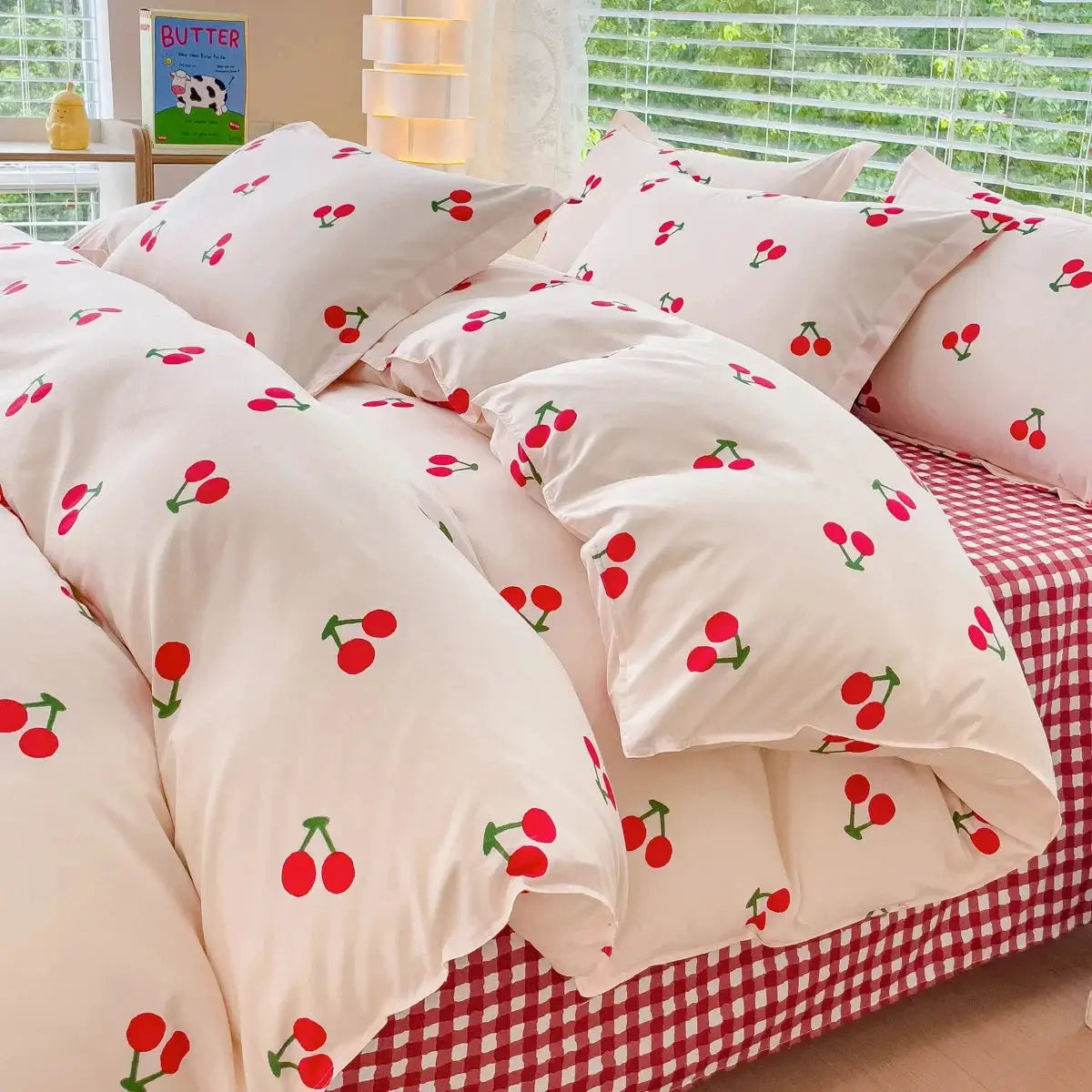Simples Market pink cherry-print bedding set with duvet cover, flat sheet and pillowcases on a gingham bed