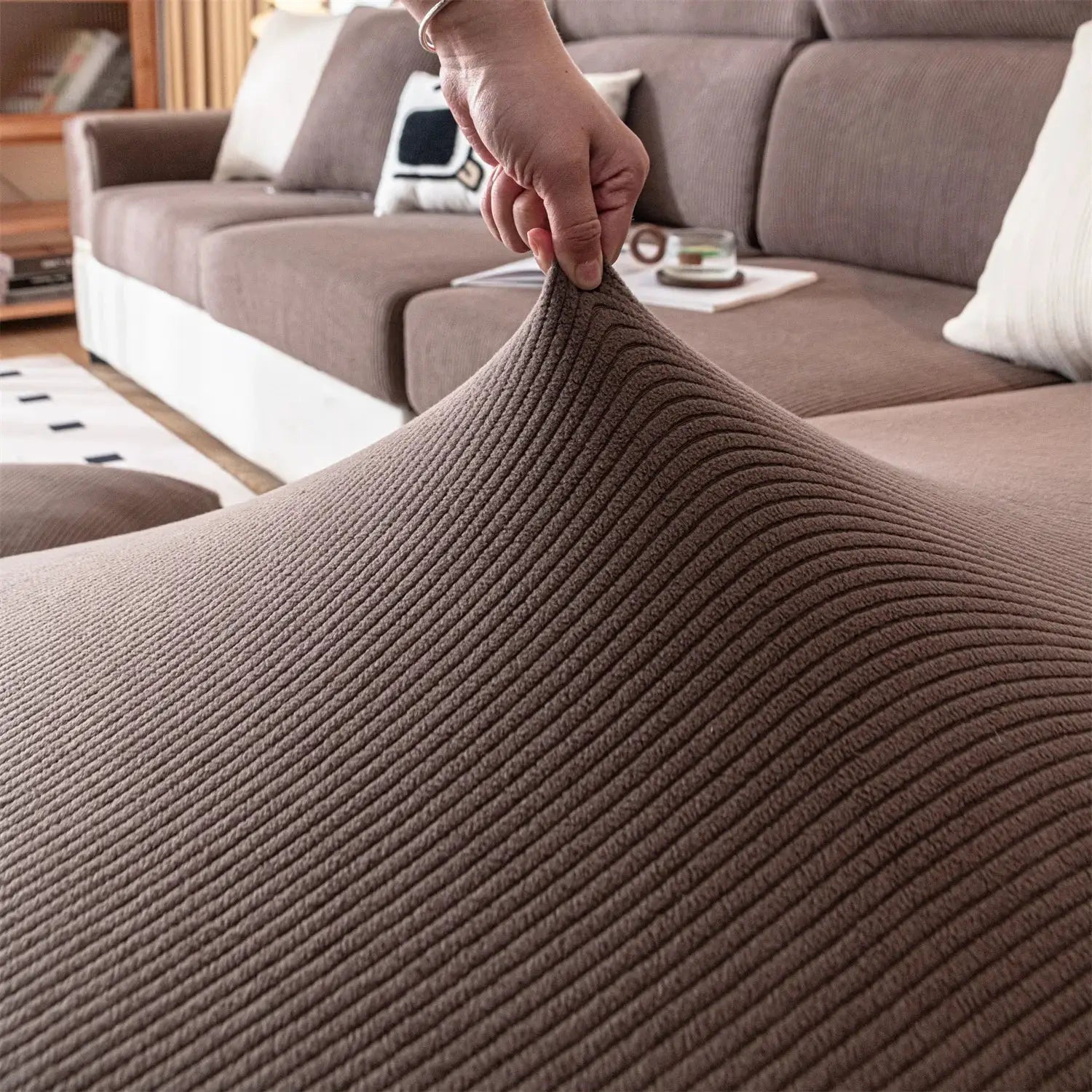 Sofa seat cushion cover in thick brown stripe jacquard fabric being stretched on a living room sofa