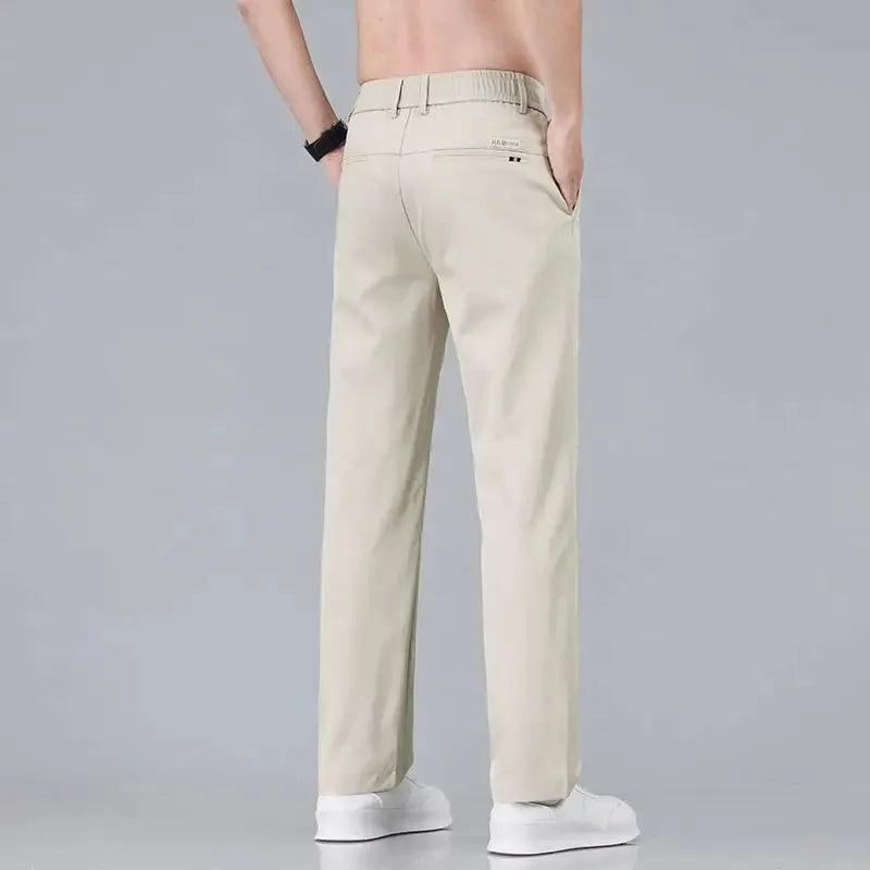 Men's beige slim-fit casual trousers in solid color, stretch cotton with back pockets, white sneakers.