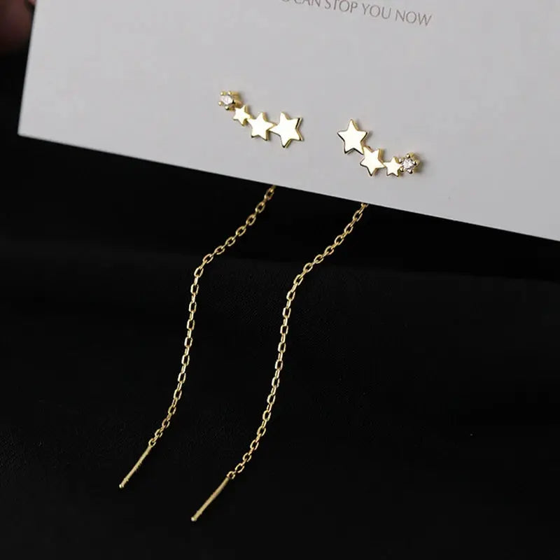 Gold-tone drop earrings with star bead pendants and long chain tassels; two-piece set