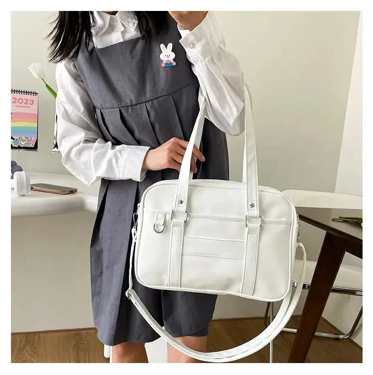 Japanese JK bag in white PU leather with dual top handles and detachable crossbody strap.