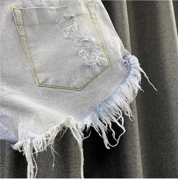 Denim shorts with distressed patches and frayed uneven hem in light wash, vintage streetwear.