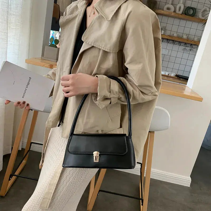 Shoulder bag by Simples Market, black solid-color handbag with gold clasp and top handle.
