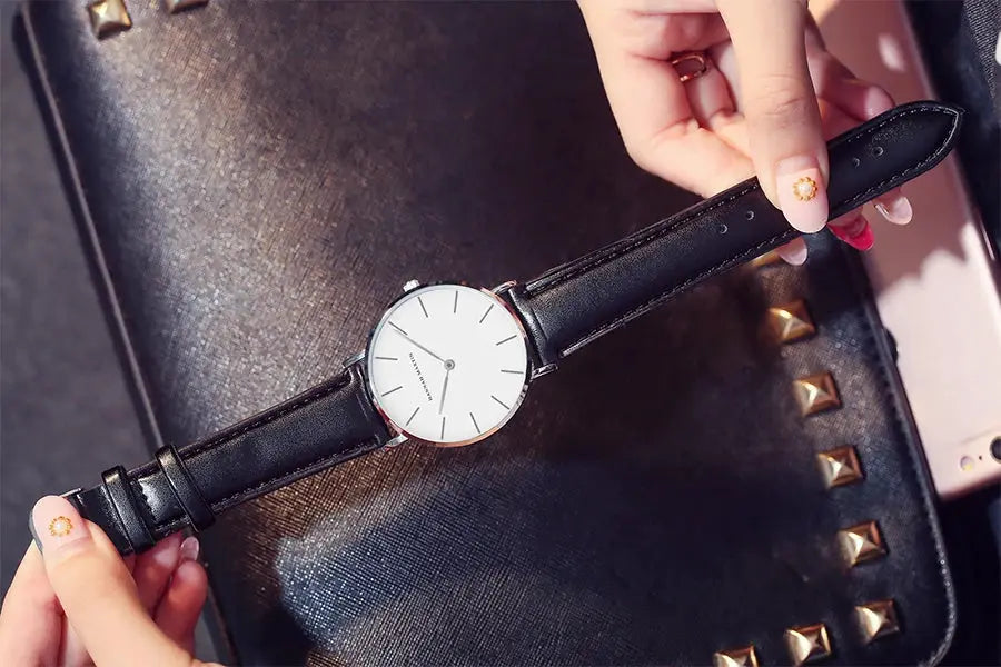 Women's watch with black leather strap, white minimalist dial, and silver case