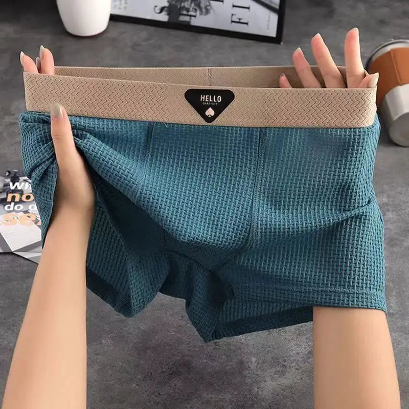 Men's teal ice-silk boxer shorts with beige elastic waistband, breathable textured fabric.