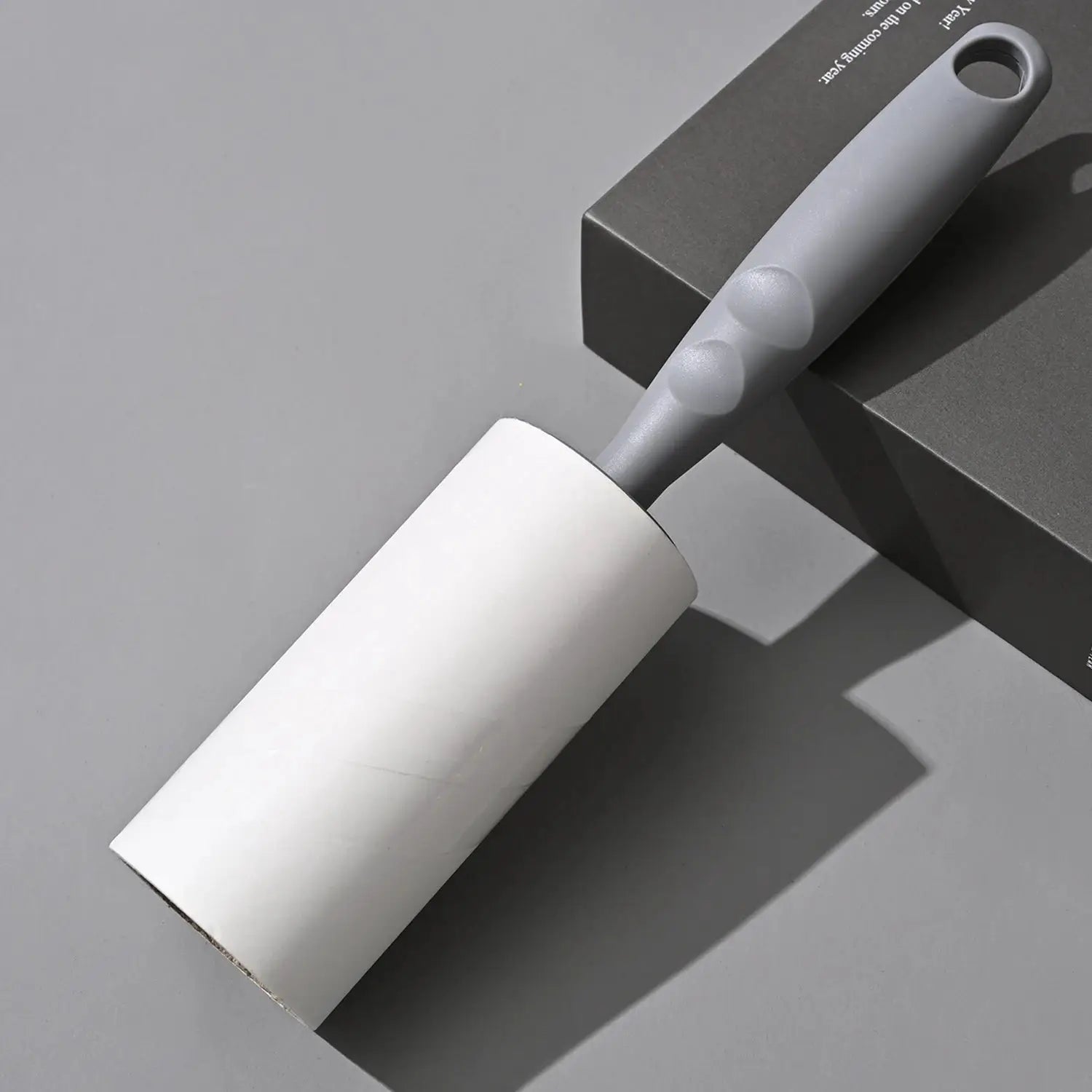Lint roller with replaceable roll; white roller on gray handle for clothing and sofa cleaning