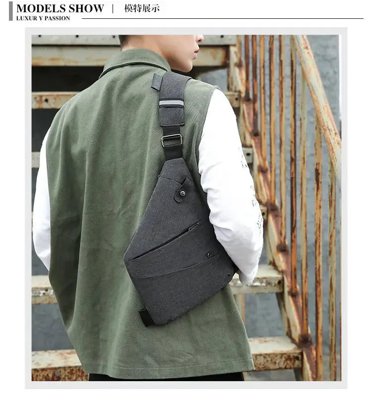 Anti-theft crossbody chest bag in dark gray fabric with front zip pocket, worn by man in a green jacket.