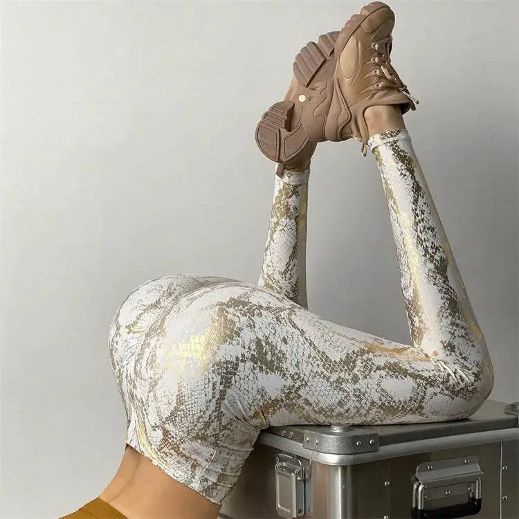 Snake-print yoga pants; white and gold high-waisted, stretchy leggings.