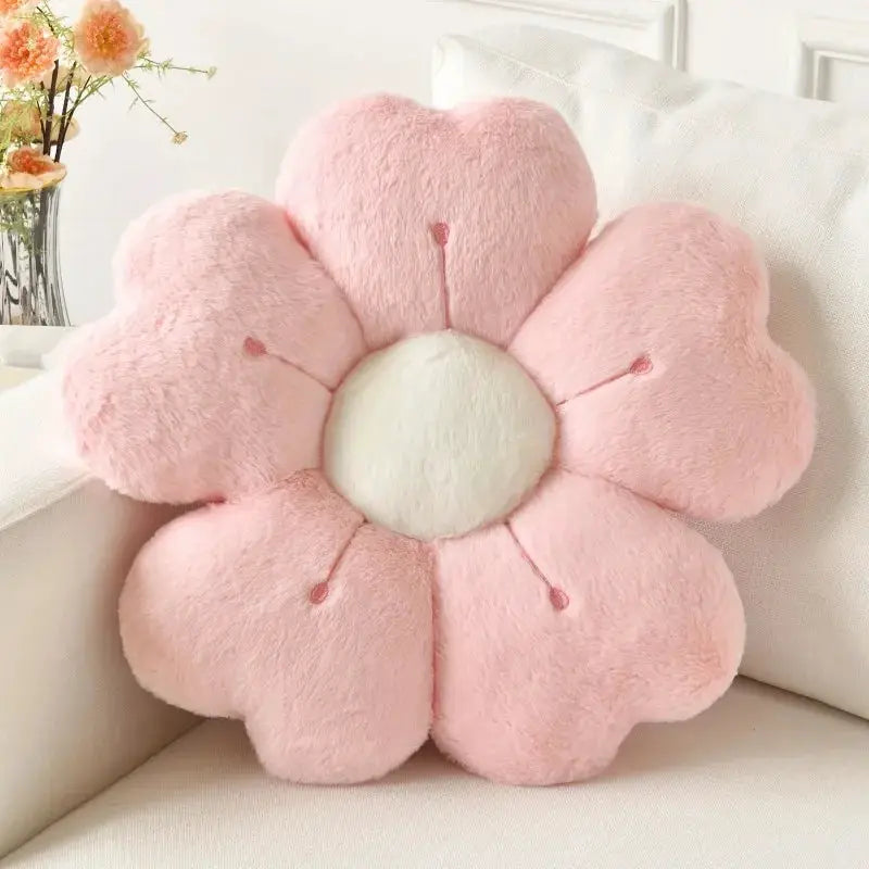 Flower-shaped pink plush throw pillow with white center on a white sofa
