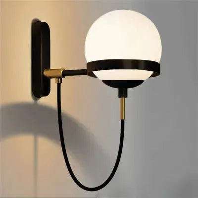 Modern glass ball wall lamp with black metal arm and brass accents for living room or bedroom