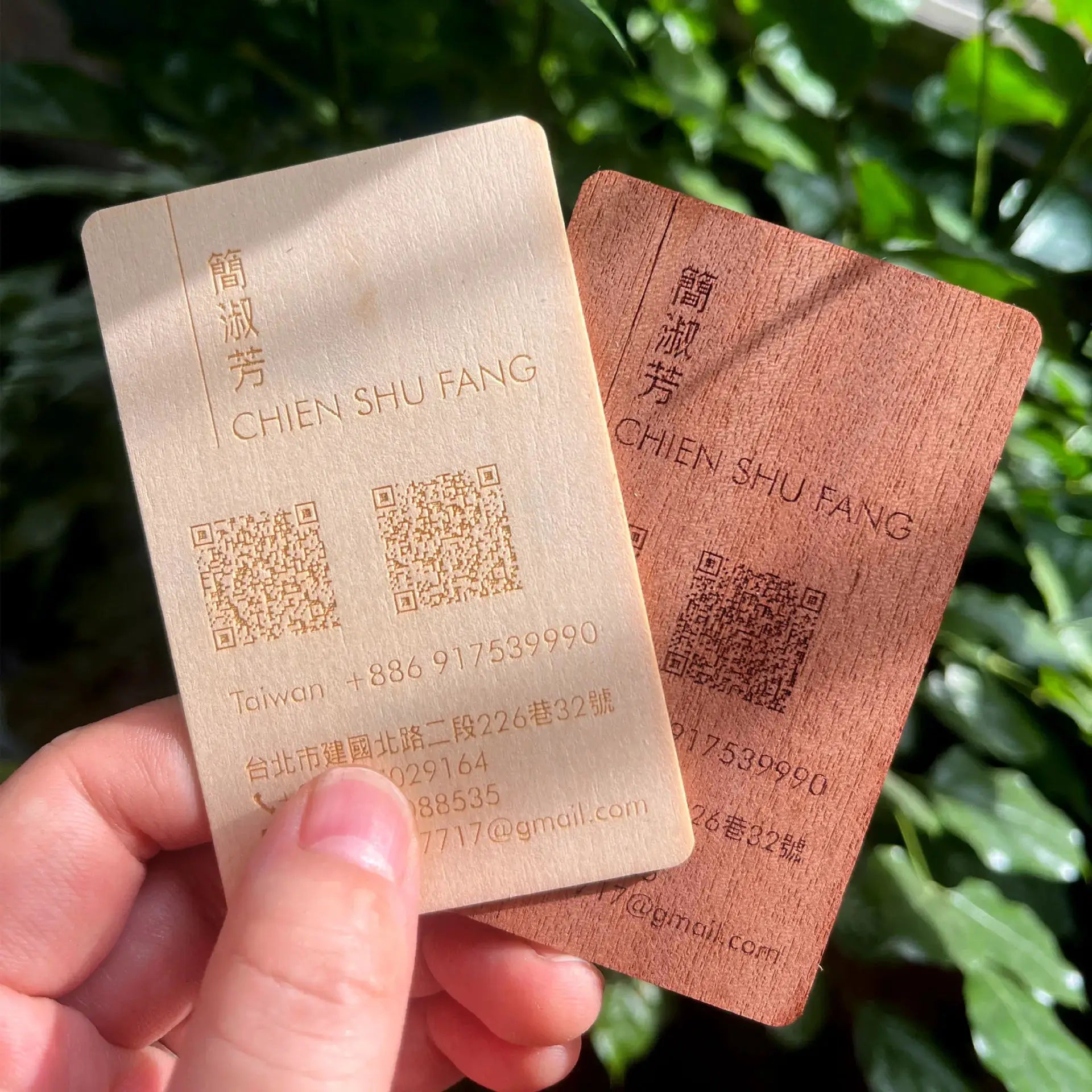 Two wooden NFC cards (beige and brown) with laser-engraved text and QR codes.