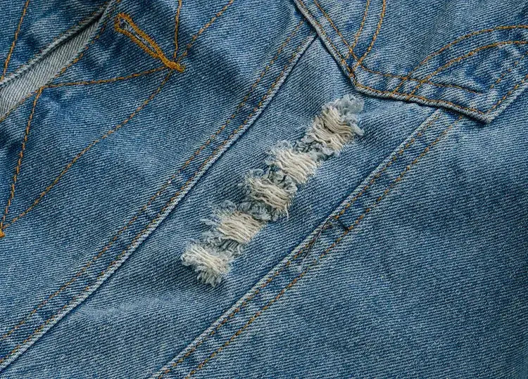 Men's light blue denim jacket with distressed ripped detail and orange stitching.