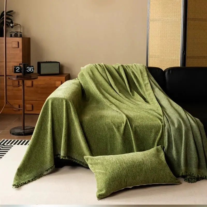 Chenille sofa throw blanket in green with tassel edge by Simples Market, draped over a sofa with a matching pillow.