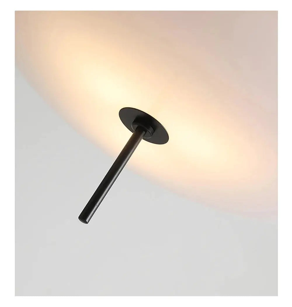 Nordic LED pendant light with flying saucer design, black cylinder stem and circular canopy, warm glow.