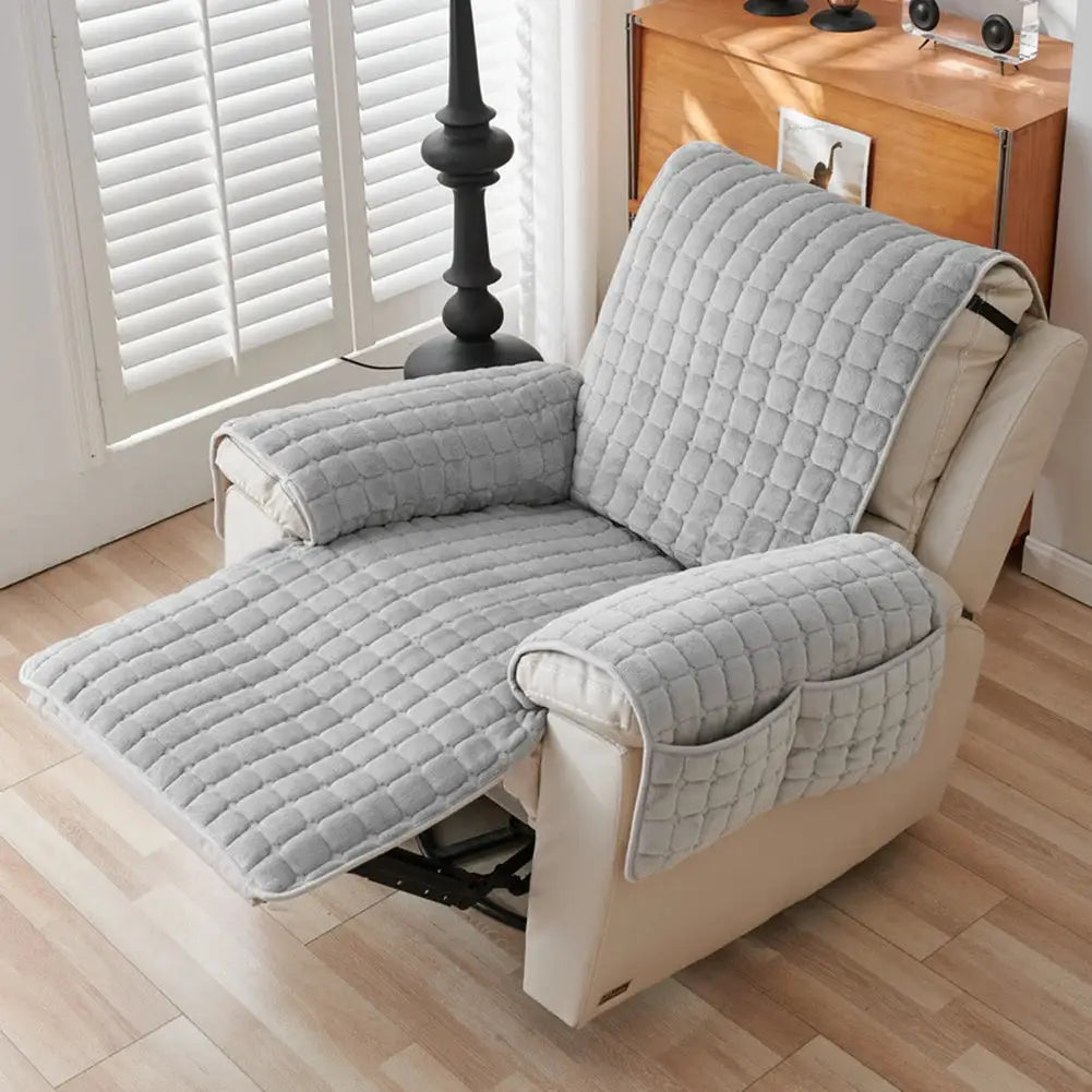 Recliner sofa protector cover with quilted gray fabric, padded armrests and armrest pockets on beige chair