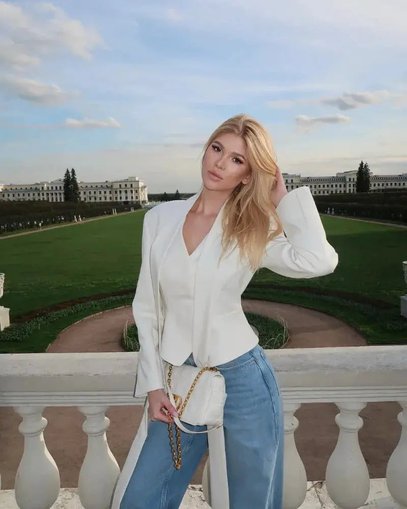 Trendix white blazer with V-neck and structured shoulders, paired with blue jeans and a white quilted handbag